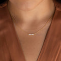A woman wearing an Initial Morse Code Necklace with small gold beads, paired with a brown v-neck blouse.