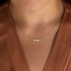 A woman wearing an Initial Morse Code Necklace with small gold beads, paired with a brown v-neck blouse.