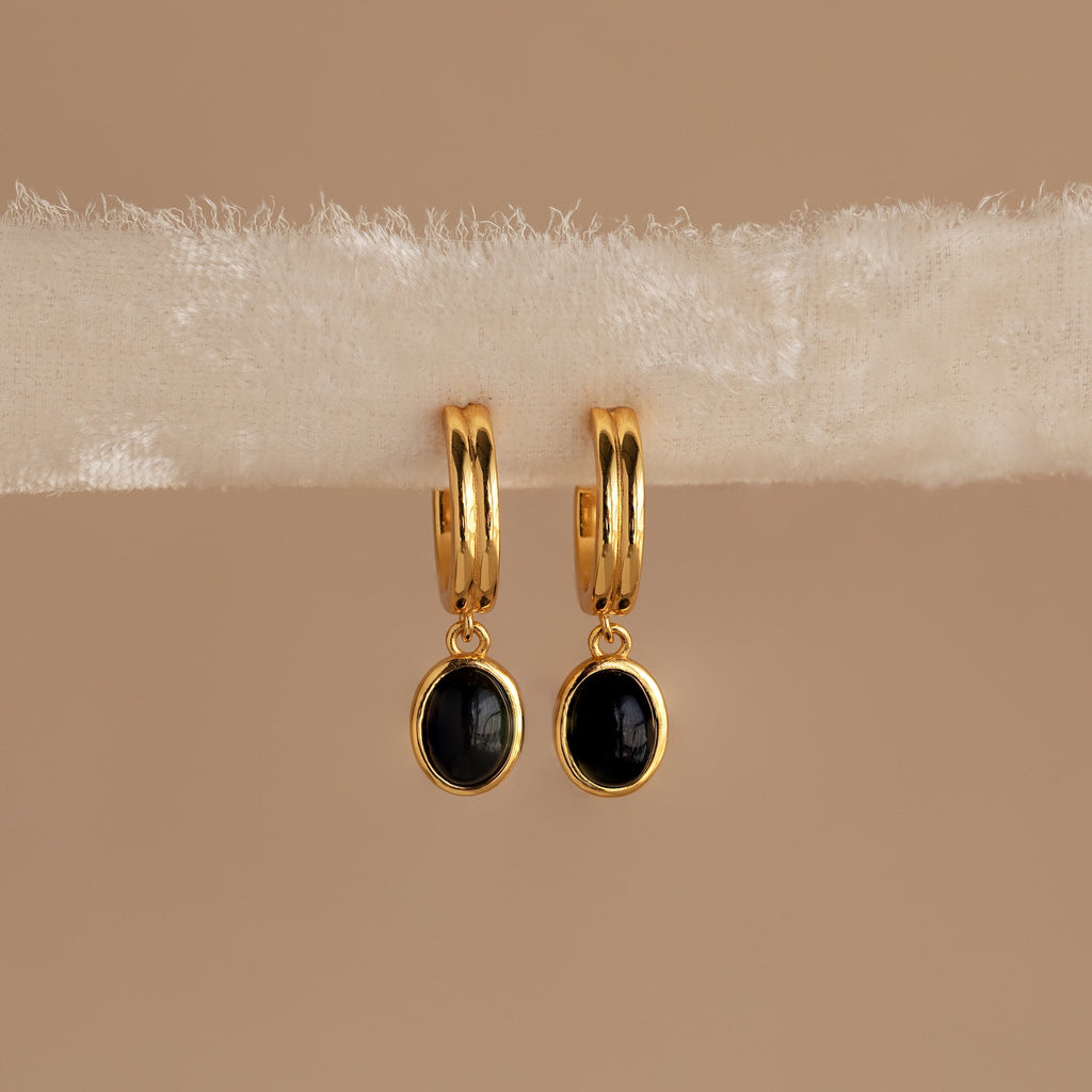 Black Onyx Hoops Bundle: Gold hoop earrings with round black onyx pendants, elegantly displayed on a cream-colored textured fabric strip.