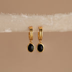 Black Onyx Hoops Bundle: Gold hoop earrings with round black onyx pendants, elegantly displayed on a cream-colored textured fabric strip.