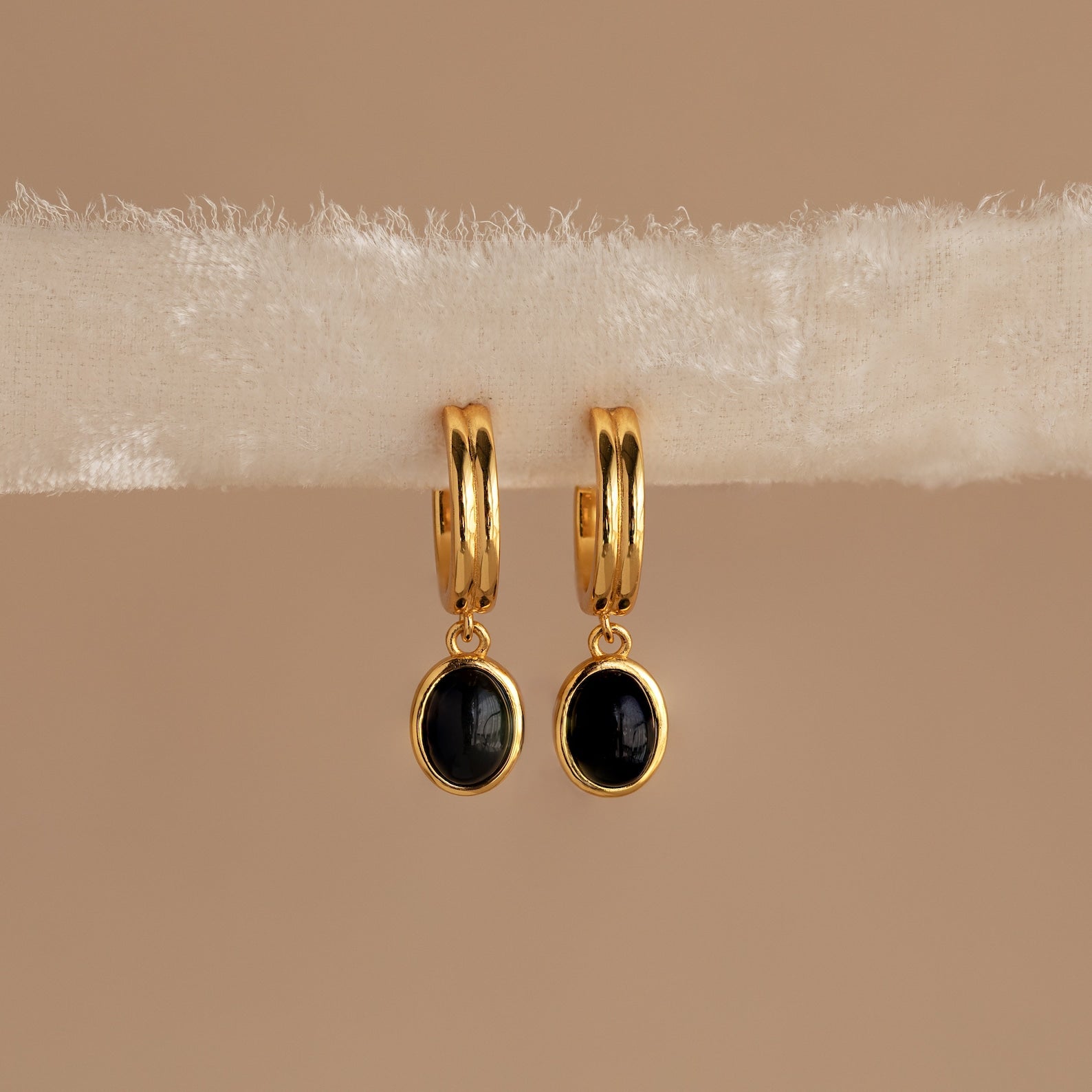 Black Onyx Hoops Bundle: Gold hoop earrings with round black onyx pendants, elegantly displayed on a cream-colored textured fabric strip.