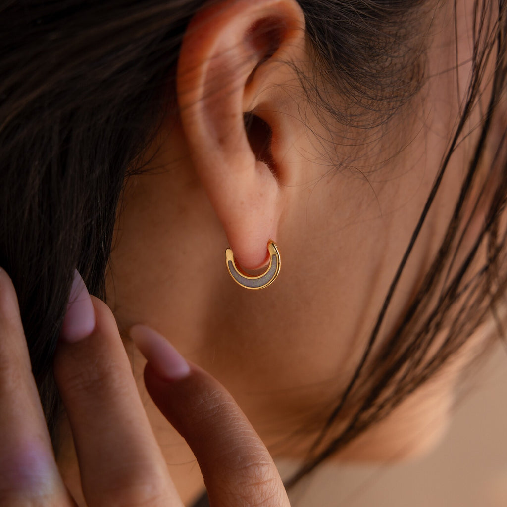 A close-up of a woman's ear adorned with Crescent Moon Opal Huggies, showcasing the luminous beauty of the opal gemstone.