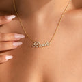 A person wears the Elegant Pave Name Necklace, customized with “Brooke” in cursive, gently holding the personalized gold accessory with manicured fingers.