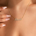 A person wears the Elegant Pave Name Necklace, customized with “Brooke” in cursive, gently holding the personalized gold accessory with manicured fingers.