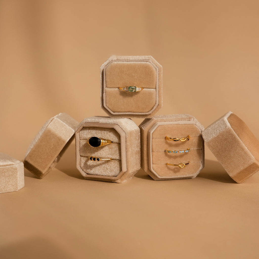 Four Velvet Ring Boxes, including one with 3 slots, showcase gold gemstone rings on a beige background—a perfect Velvet Ring Box set for presenting and gifting your favorite jewelry pieces.