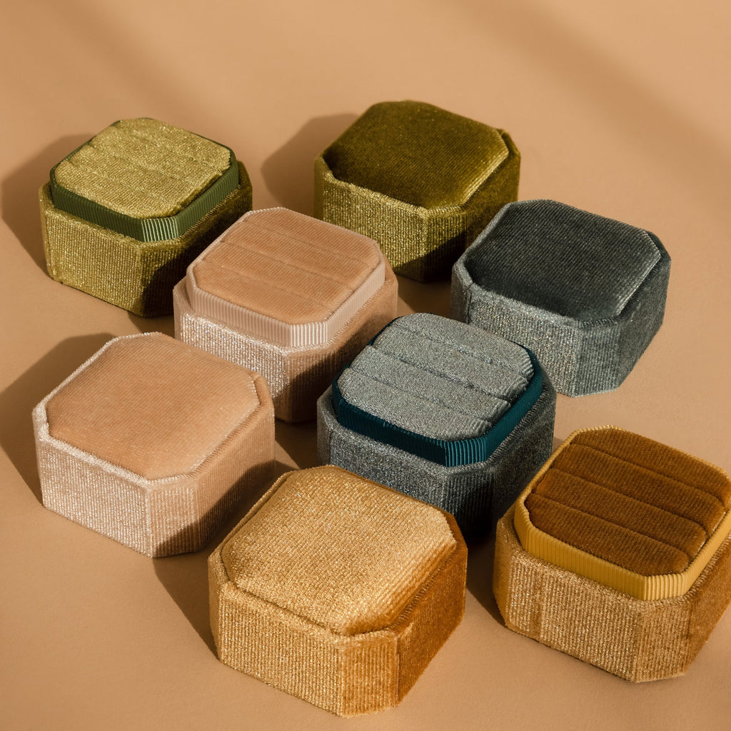 Nine Velvet Ring Boxes in assorted colors are arranged on a tan surface with soft shadows, creating a charming display that's perfect for showcasing your Velvet Ring Box collection.
