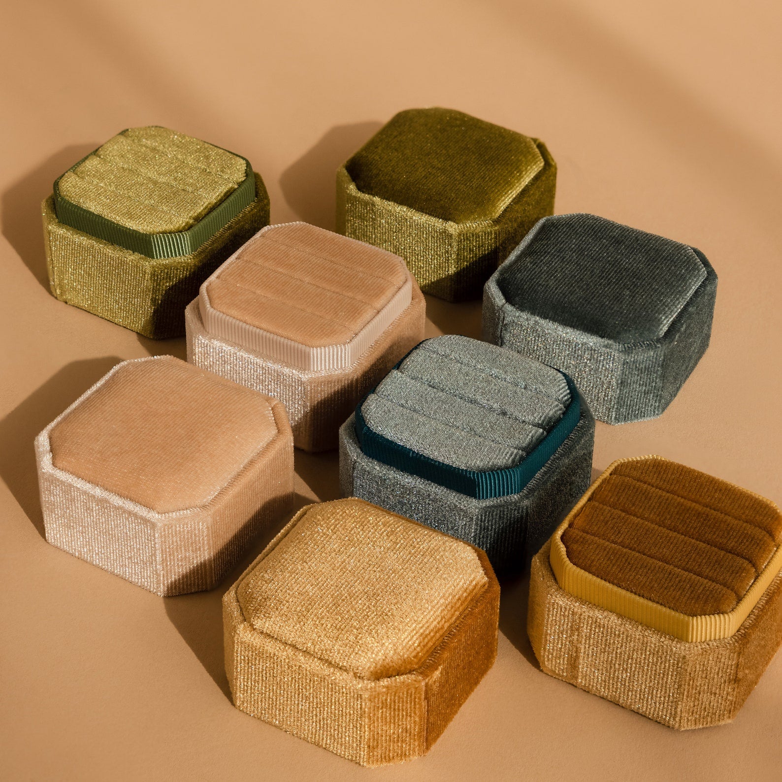 Nine Velvet Ring Boxes in assorted colors are arranged on a tan surface with soft shadows, creating a charming display that's perfect for showcasing your Velvet Ring Box collection.