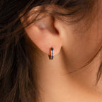 Close-up of a person’s ear adorned with a small, multicolored Opal Inlay Earring from the Opal Collection.