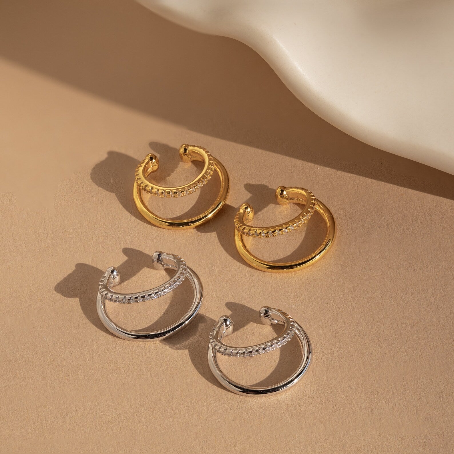 The Lydia Duo Cuffs feature two pairs of hoop earrings—one gold, one silver—with chain detail, ideal for layering with your favorite earrings or styling alongside a golden ear cuff for a chic look.