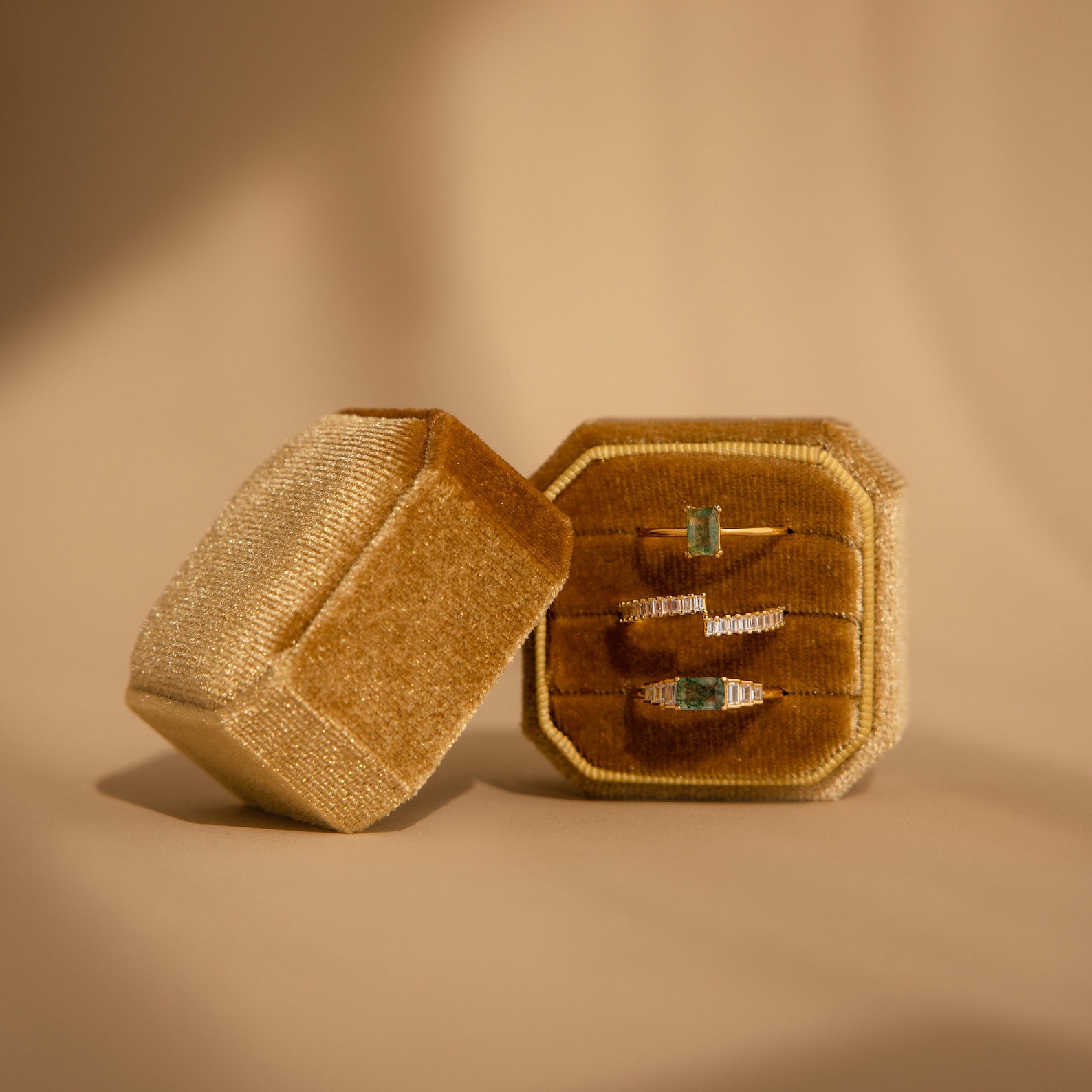 The Velvet Ring Box, shown in tan with three gemstone rings against a beige background, features three slots and is perfect for elegantly showcasing your finest jewelry pieces.