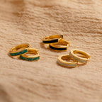 The Opal Inlay Hoops Set and wedding earrings are elegantly displayed on a soft fabric surface.