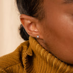 Close-up of a person wearing the Daydreamer Diamond Studs with a mustard yellow turtleneck sweater.