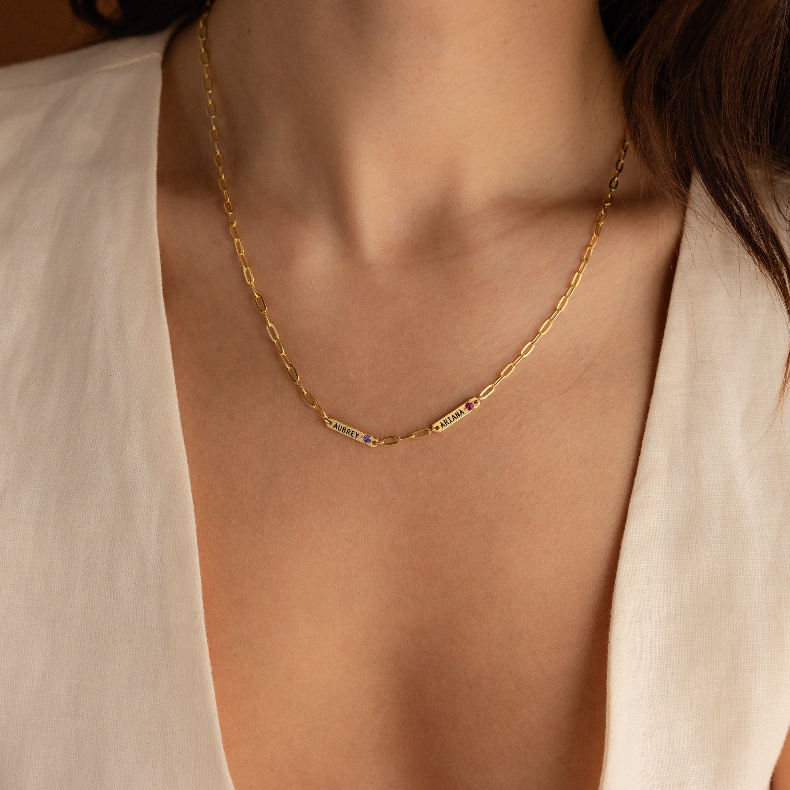 The Mini Name Birthstone Necklace, featuring a delicate bar accent, pairs stylishly with a v-neck white blouse—a chic close-up and perfect as a personalized or customized gift.