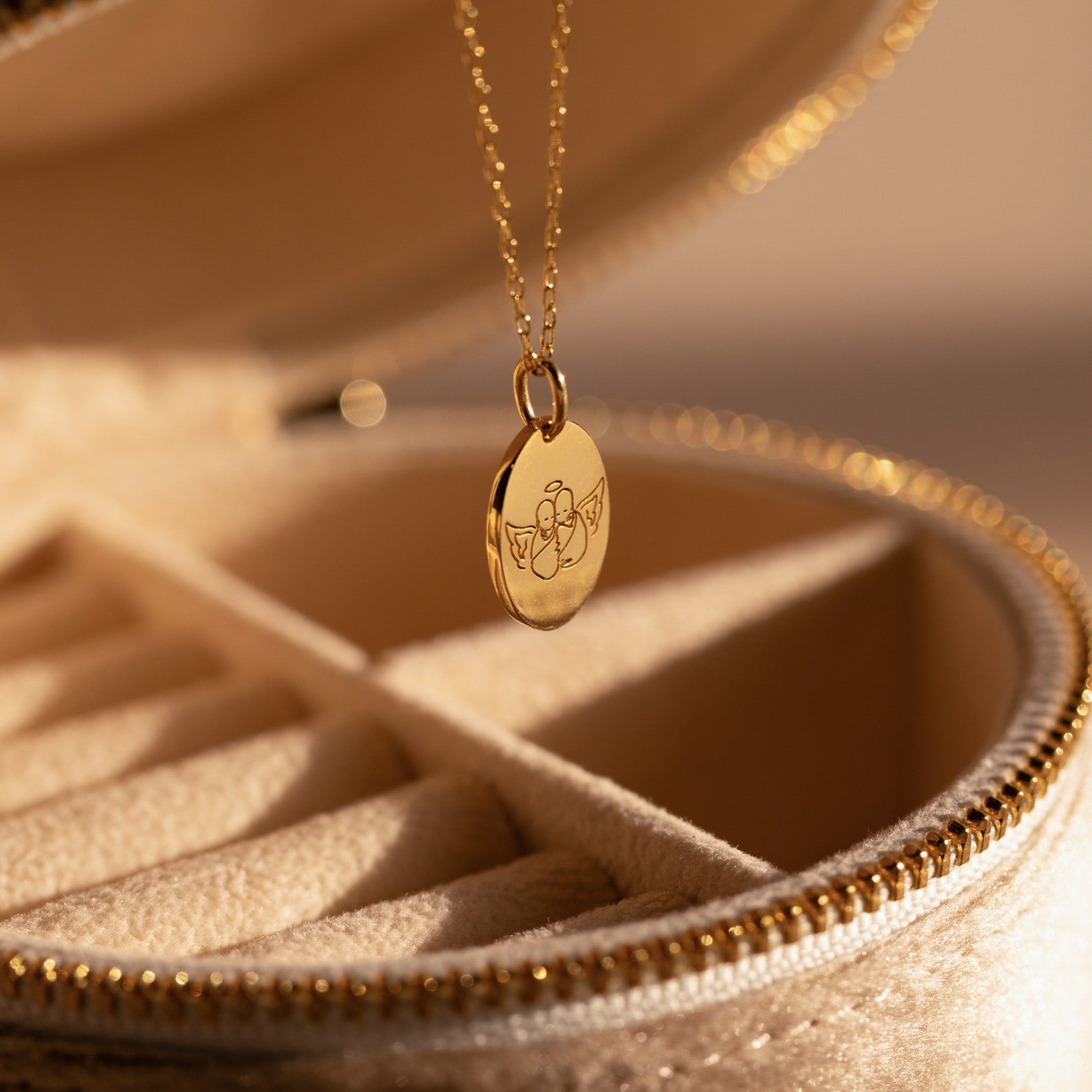 Child Portrait Necklace, a gold engraved pendant showcasing a child's portrait, elegantly displayed on a beige jewelry box with zipper detail.