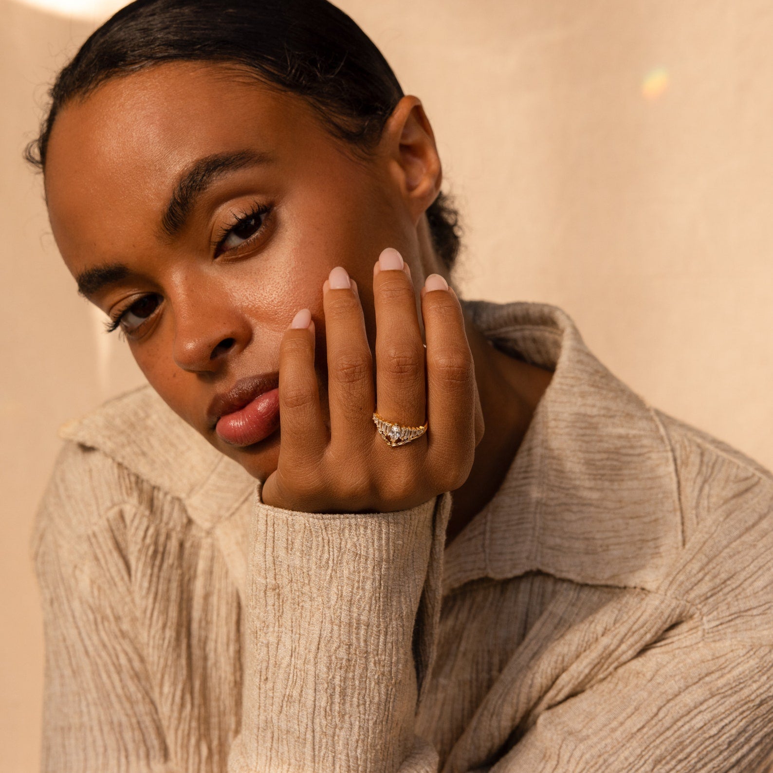 A woman with short hair in a beige shirt showcases the Art Deco Ring Set on her fingers while looking at the camera.