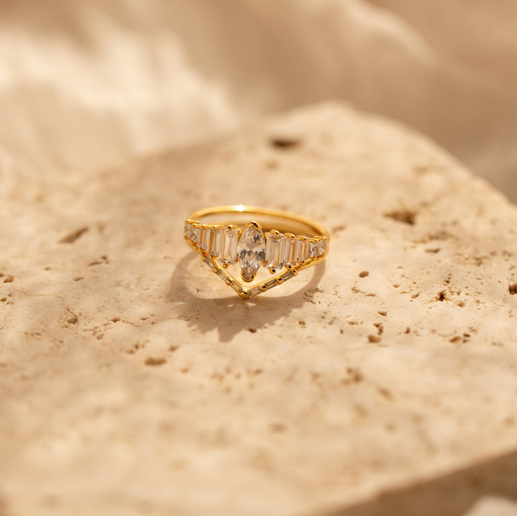 The Art Deco Ring Set, featuring clear gemstones, rests on a textured beige stone surface in soft lighting.