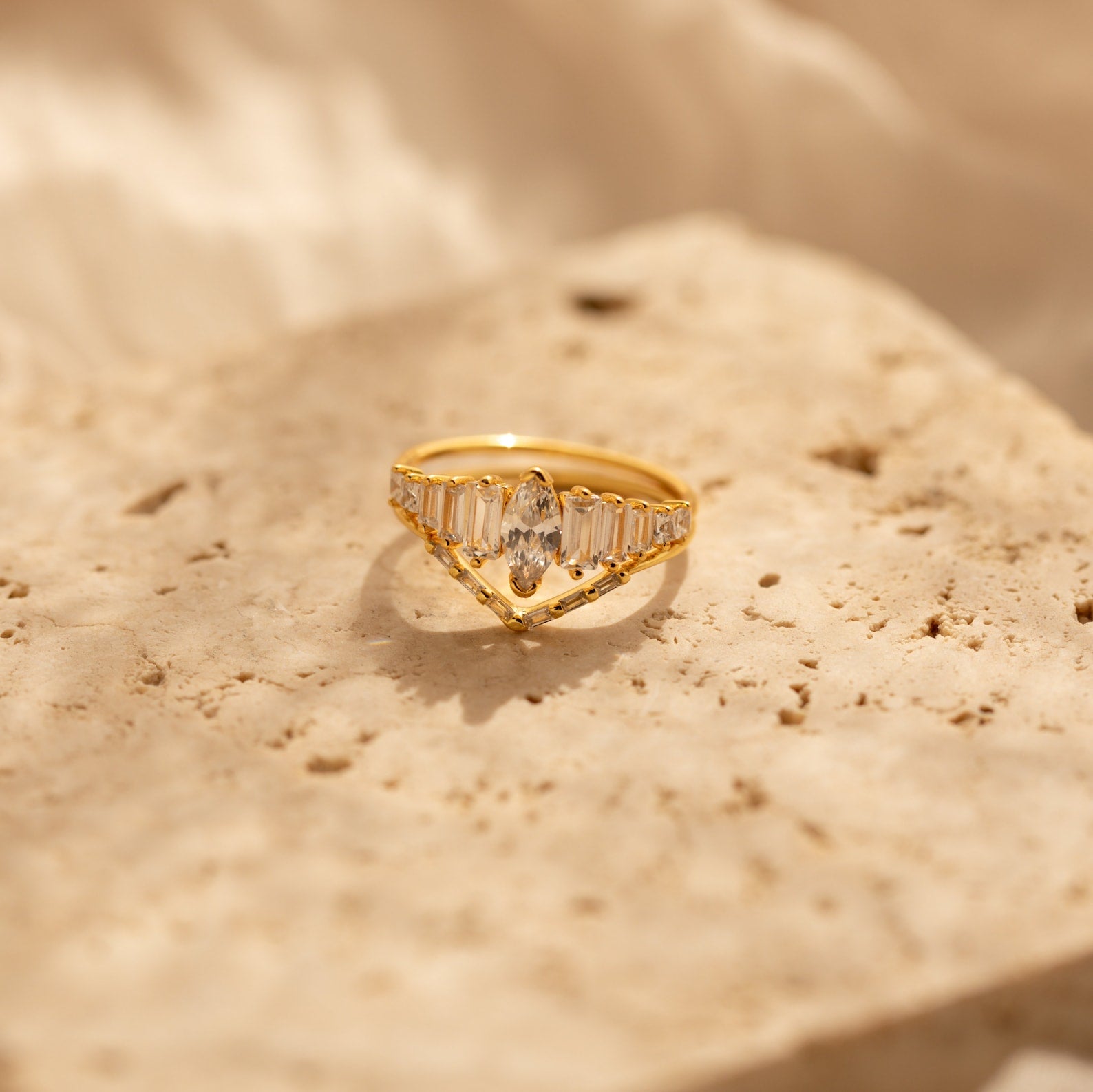 The Art Deco Ring Set, featuring clear gemstones, rests on a textured beige stone surface in soft lighting.