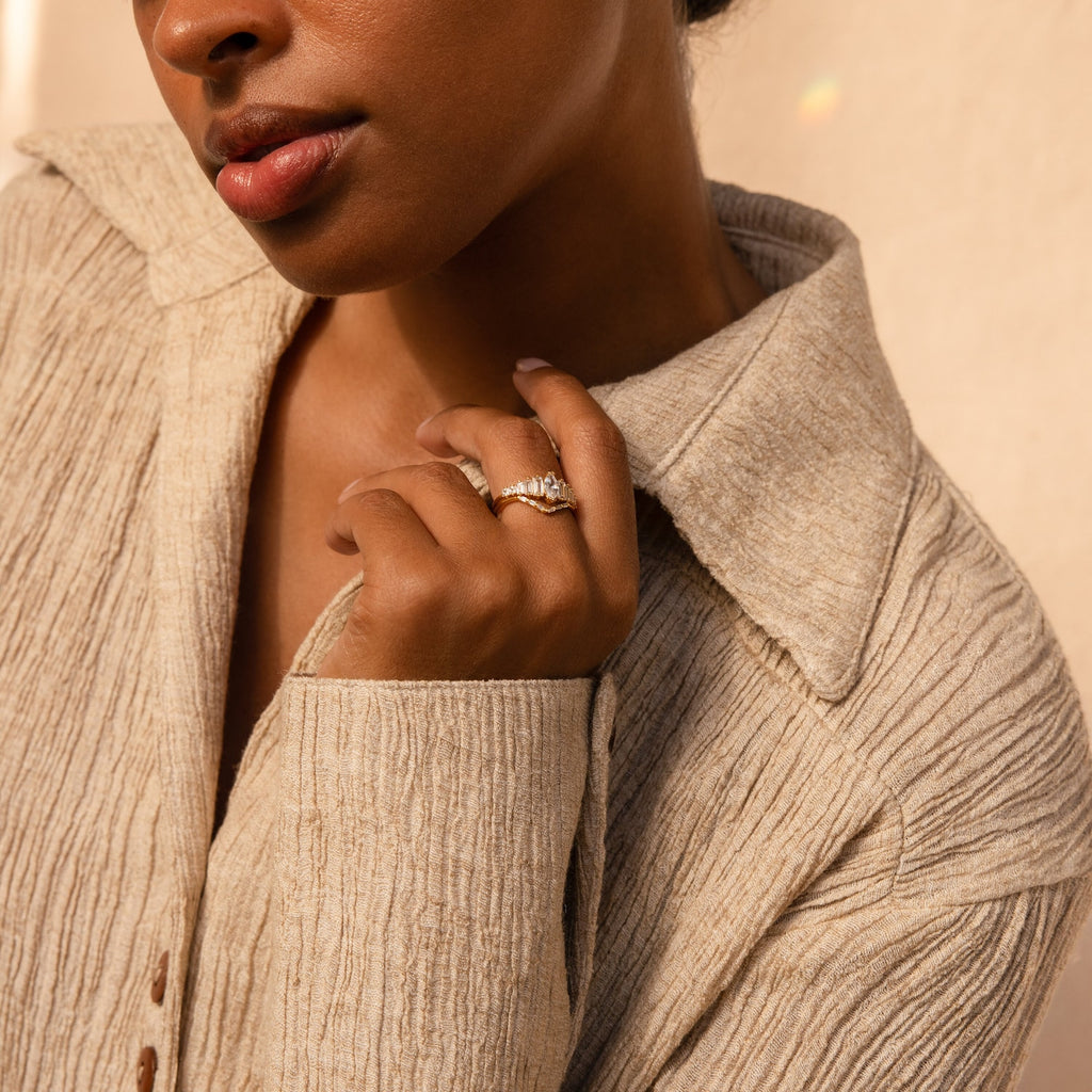 A woman in a beige textured shirt showcases the elegant Art Deco Ring Set and wedding band on her left hand.