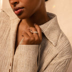 A woman in a beige textured shirt showcases the elegant Art Deco Ring Set and wedding band on her left hand.