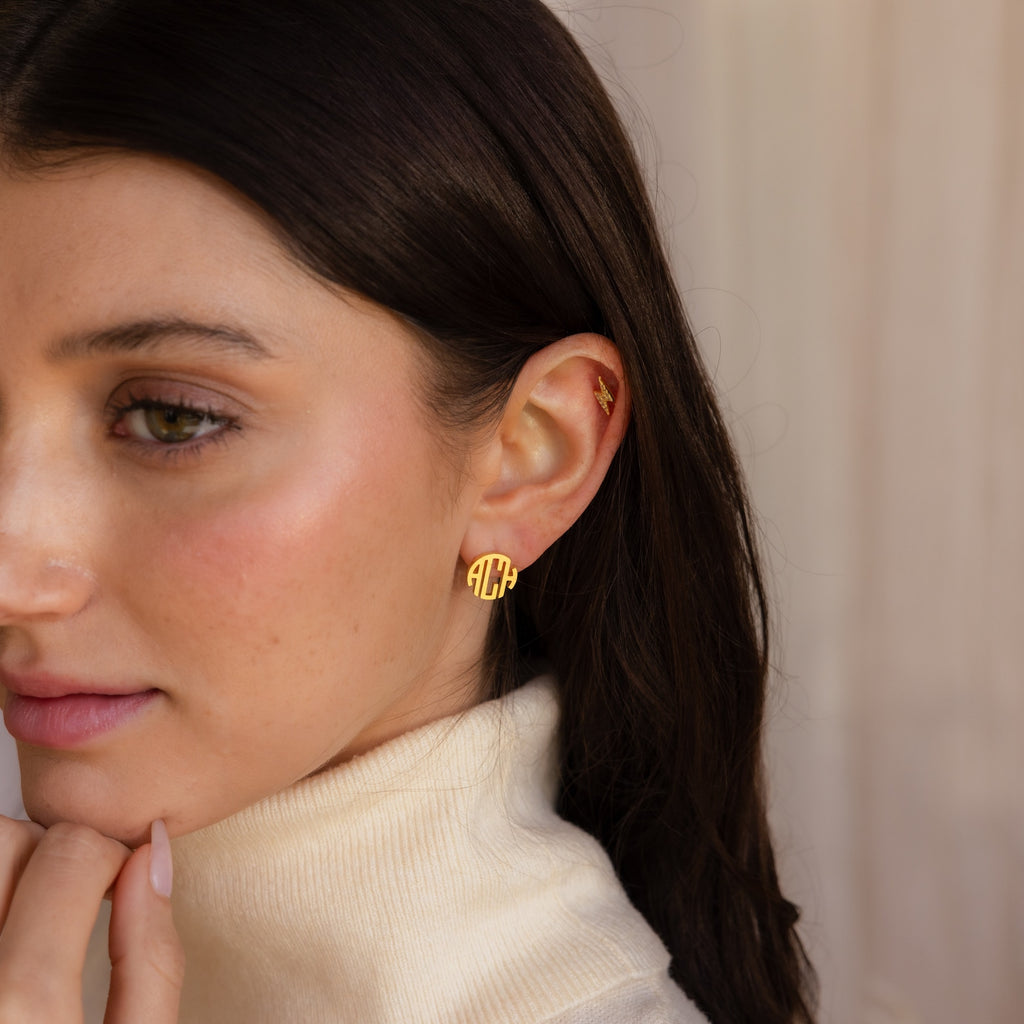 Woman with long dark hair wearing a cream turtleneck and an elegant earring stack featuring the Block Monogram Earrings, looking to the side.