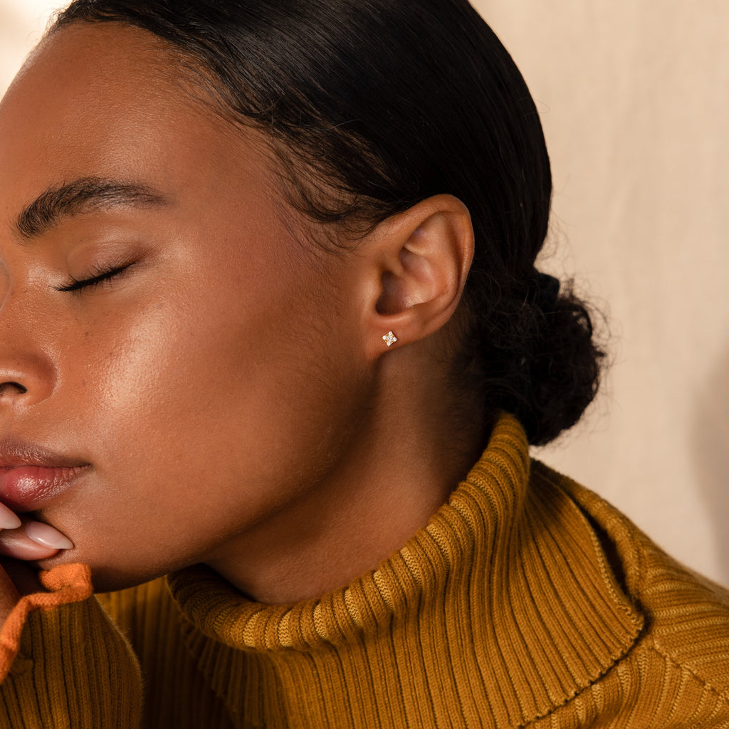 A woman in a mustard turtleneck with closed eyes showcases the Daydreamer Diamond Studs.