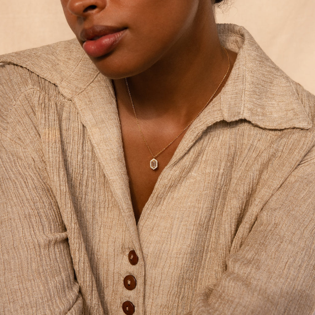 Woman in a textured beige shirt with brown buttons, wearing the Daydreamer Diamond Necklace—a luxury piece that exudes timeless elegance—facing slightly sideways.