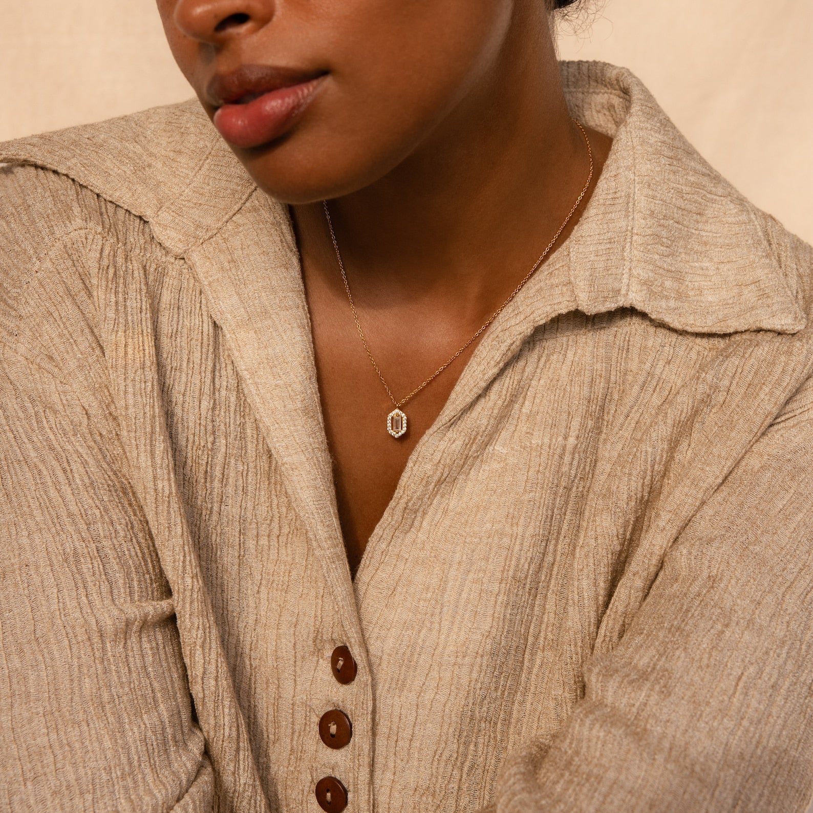 Woman in a textured beige shirt with brown buttons, wearing the Daydreamer Diamond Necklace—a luxury piece that exudes timeless elegance—facing slightly sideways.