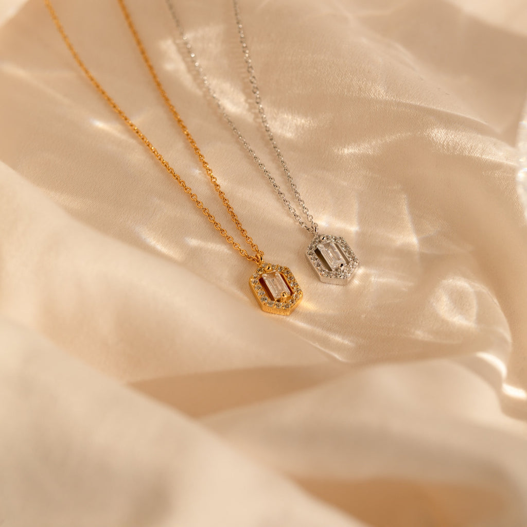 The Daydreamer Diamond Necklace, shown in both gold and silver with rectangular pendants on soft beige fabric, radiates timeless elegance and luxurious charm.