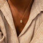 The Daydreamer Diamond Necklace, featuring a small hexagonal pendant inspired by Art Deco style, adds elegance when layered over a beige textured shirt.