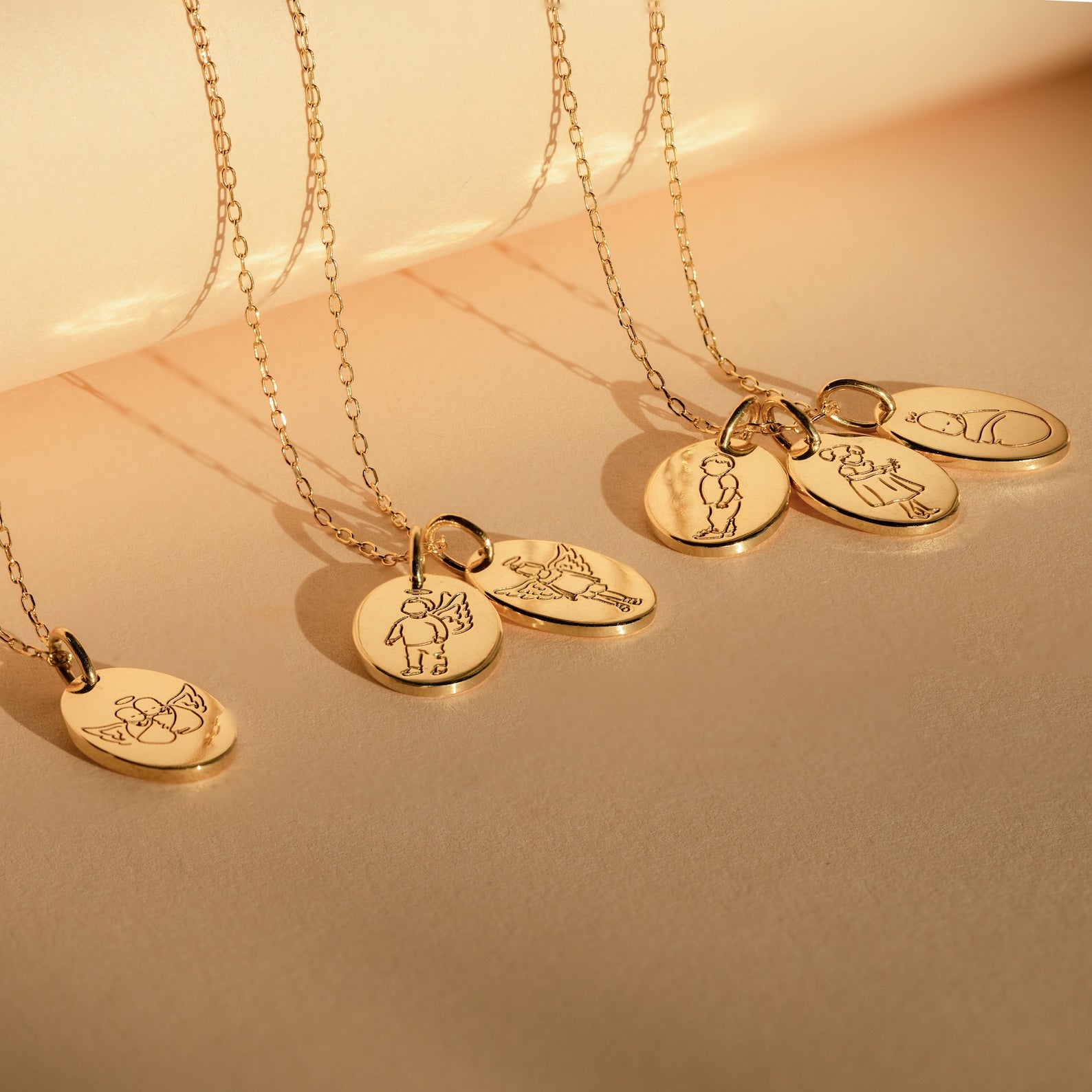 The Child Portrait Necklace is a gold engraved necklace with an oval pendant featuring minimalist line art of people or animals, ideal as a memorial piece or personalized keepsake, shown on a beige background.