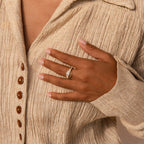 A hand with French-manicured nails wears the Art Deco Ring Set, resting on a beige textured button-up shirt.