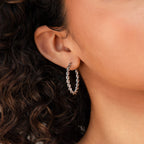 Close-up of a woman's ear adorned with Bold Twisted Hoops, showcasing their striking twist design and curly hair in view.