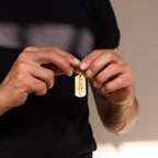 Someone in a black shirt holds a Handwriting Dog Tag Keychain featuring personalized engraved writing in their hands.