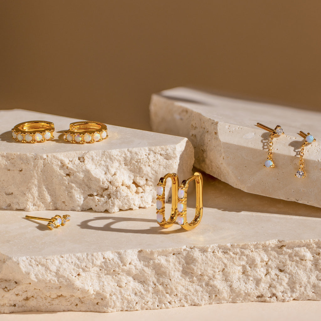 Dainty Opal Earrings showcased on light stone slabs with a soft beige background.