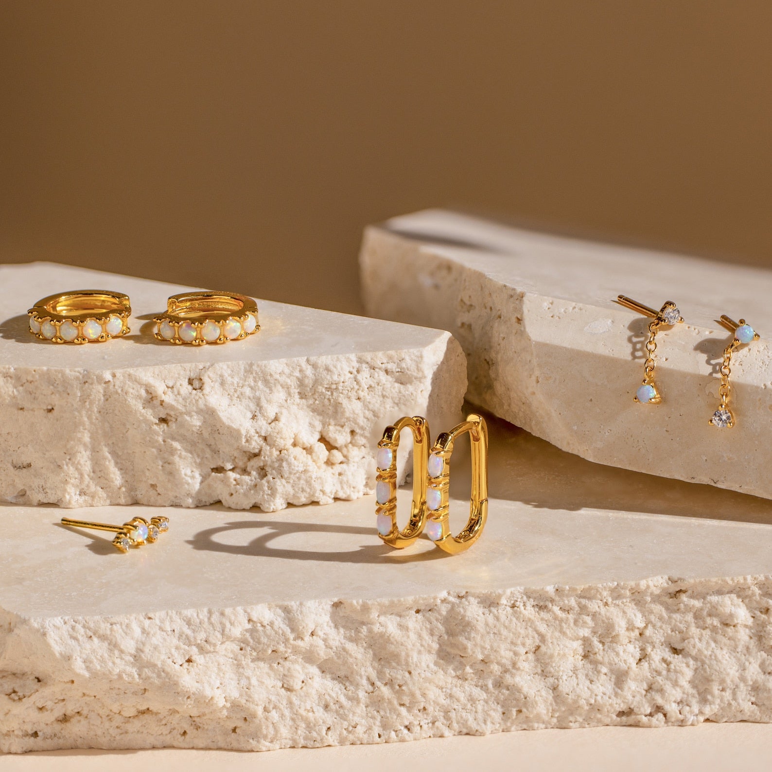 Dainty Opal Earrings showcased on light stone slabs with a soft beige background.
