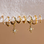 Six pairs of Dainty Opal Earrings featuring gold hoops with unique designs and gemstone accents, including genuine opal details, are displayed on a white textured surface.