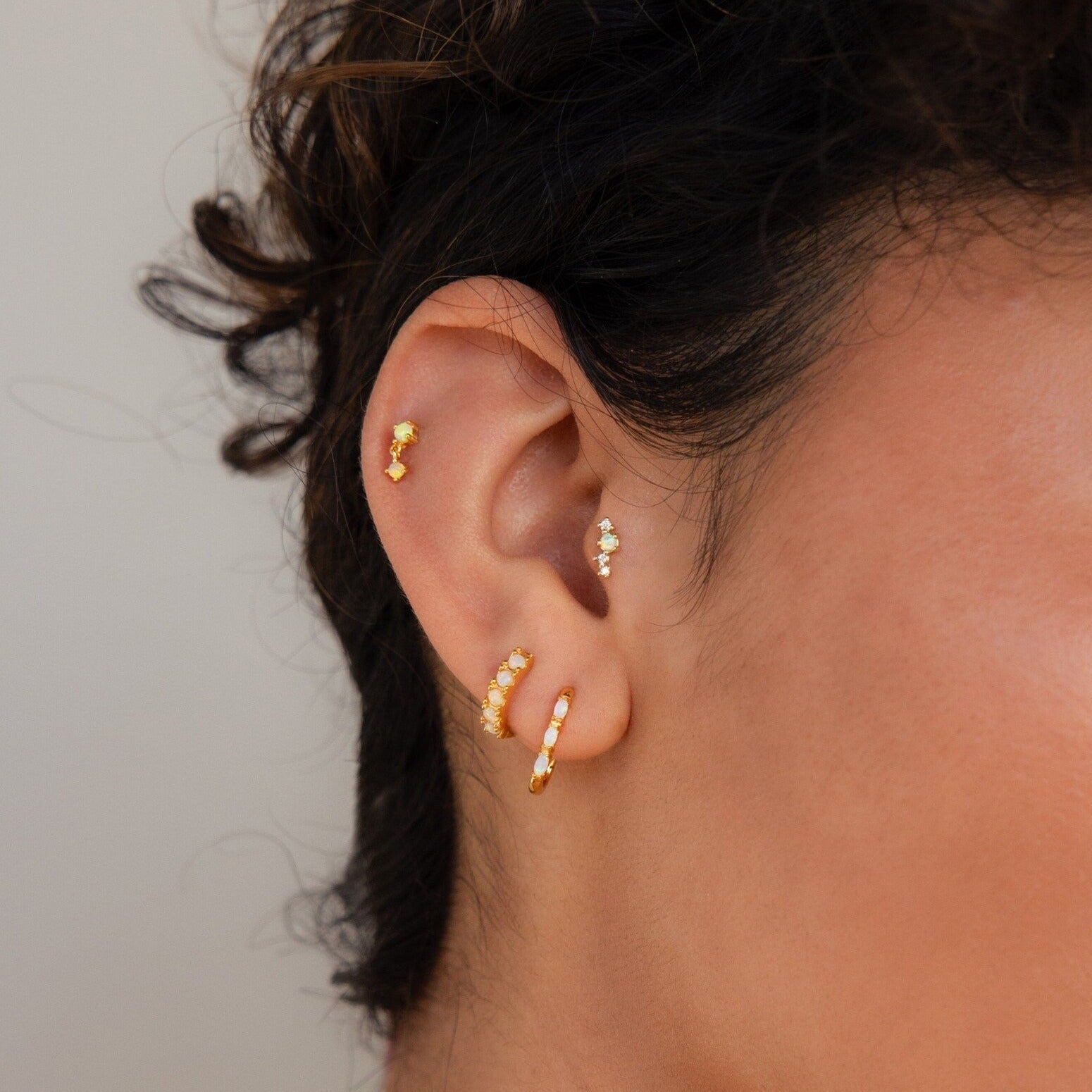 Close-up of an ear wearing Dainty Opal Earrings and diamond studs in multiple piercings, highlighting the elegance of genuine opal paired with sparkling diamonds.