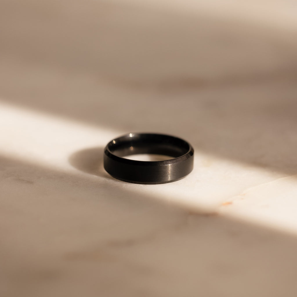 The Classic Men's Black Rings Set, ideal for men's jewelry collections, is displayed on a sunlit, light-colored marble surface with soft shadows.