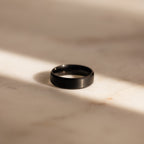 The Classic Men's Black Rings Set, ideal for men's jewelry collections, is displayed on a sunlit, light-colored marble surface with soft shadows.