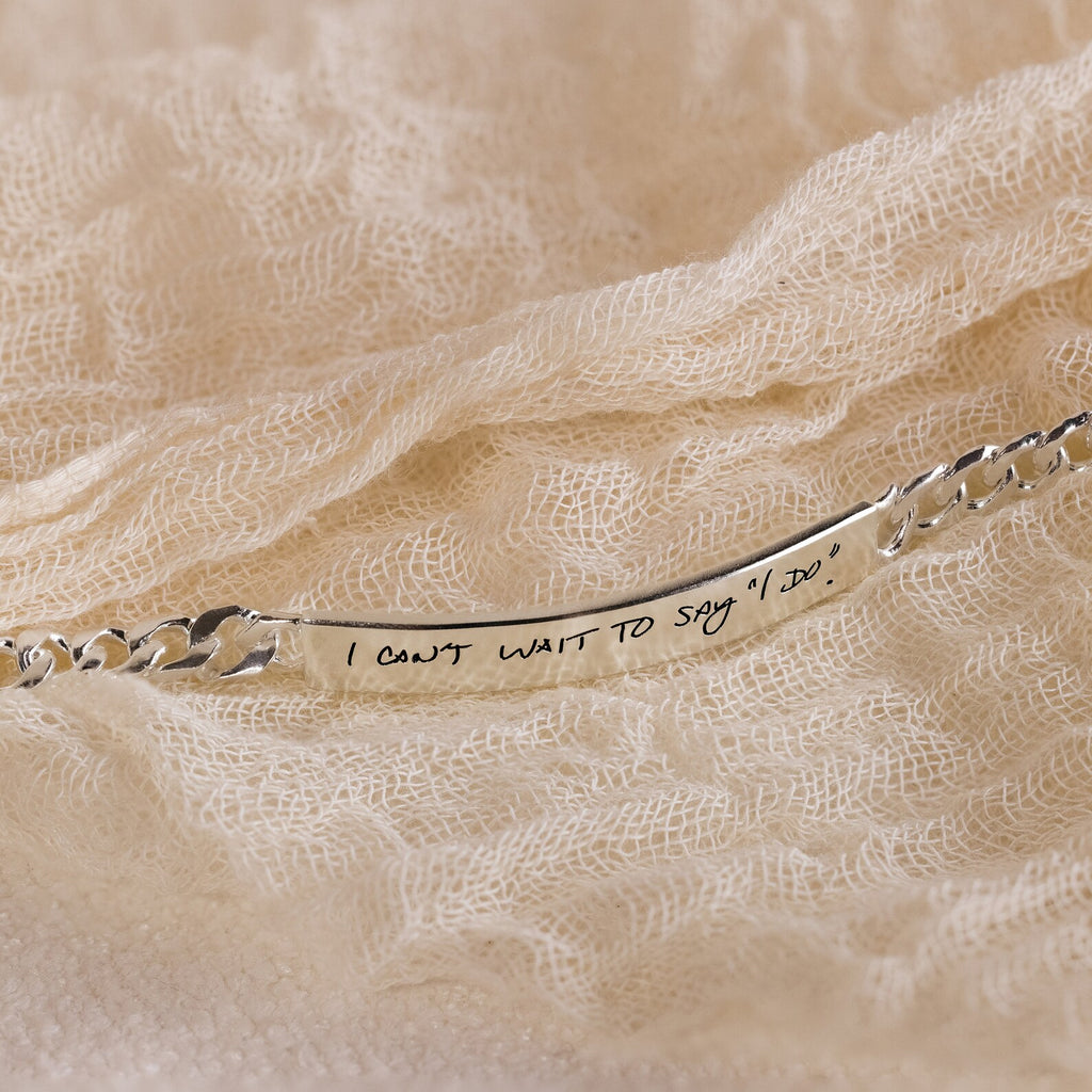 The Men's Engraved Bar Bracelet, engraved with “I can’t wait to say ‘I do’,” features a silver finish on textured cream fabric—an ideal memorial gift or keepsake for cherished moments.