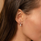 Close-up of a woman's ear wearing the Pearl Knot Necklace & Earrings Set in Sterling Silver, featuring delicate pearl drops—ideal for weddings or pairing with other pearl jewelry.