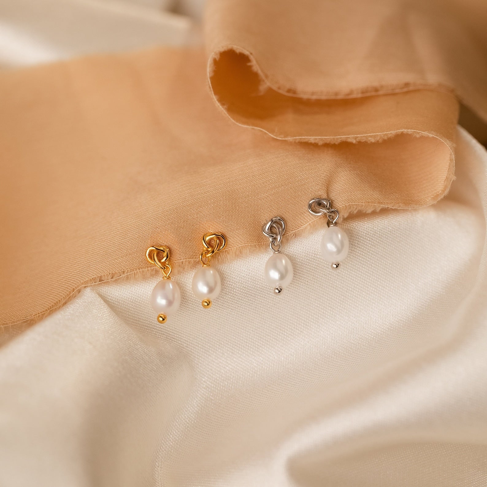 The Knot Pearl Necklace & Earrings Set, featuring gold and silver pearl earrings displayed on beige and cream fabric—an elegant gift for her.