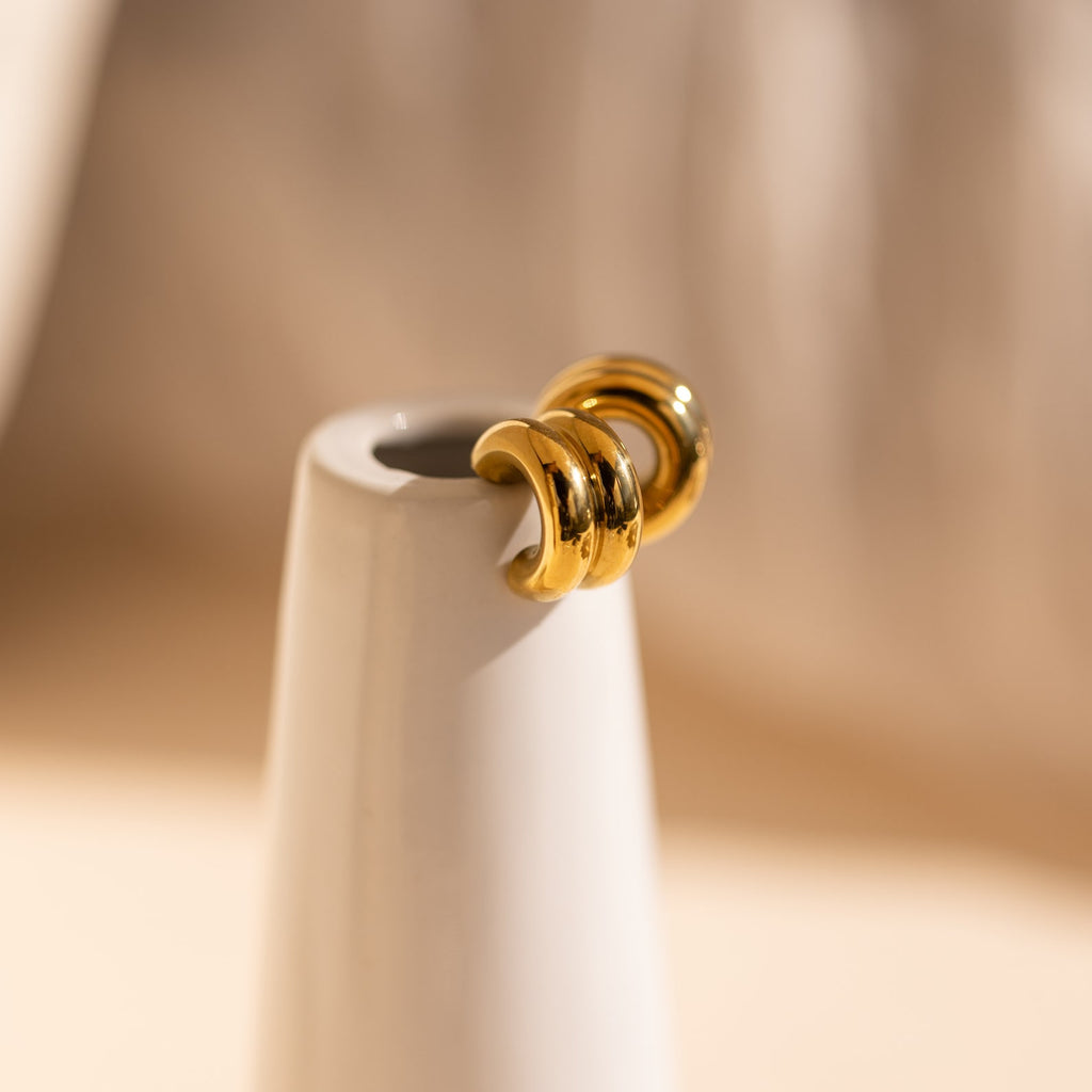 Chunky Double Hoops are displayed on a sleek white ceramic vase under soft lighting, creating a bold statement for fans of minimalist jewelry.