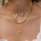 A woman wearing layered gold necklaces, featuring the Cowboy Boot Necklace—a western-style piece with a small engraved boot pendant.