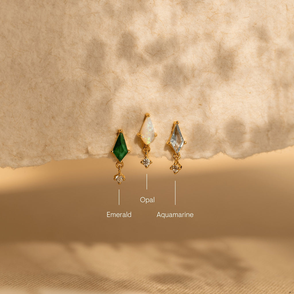 A row of gemstone earrings in various shapes and colors, including Art Deco Drop Studs, CZ Diamond, and Kite Gemstone Studs.