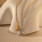 The Cowboy Boot Necklace comes in gold and silver with a western boot pendant, displayed on a curved beige surface—perfect for adding charm to your look.