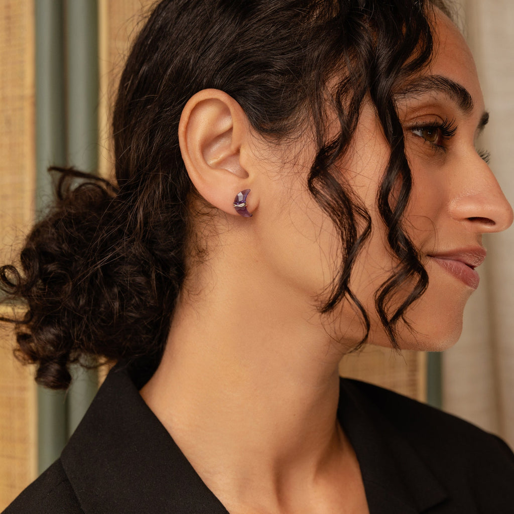 Model showcases a purple moon-shaped earring in silver. 