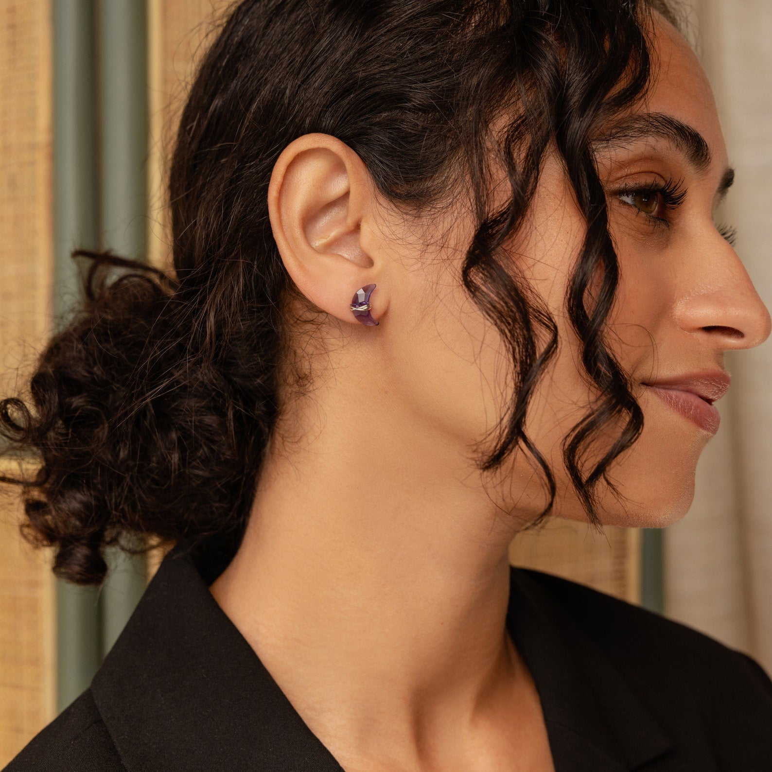 Model showcases a purple moon-shaped earring in silver. 