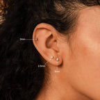 Close-up of an ear wearing the Diamond Flatback Studs Set—three dainty earrings in 2mm, 2.5mm, and 3mm sizes—displayed on different parts of the ear.
