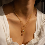 Close-up of a woman wearing the Celestial Pendant Necklace Set—layered gold necklaces with sun, moon, and crystal charms—styled over a white blouse; an elegant gift for her.